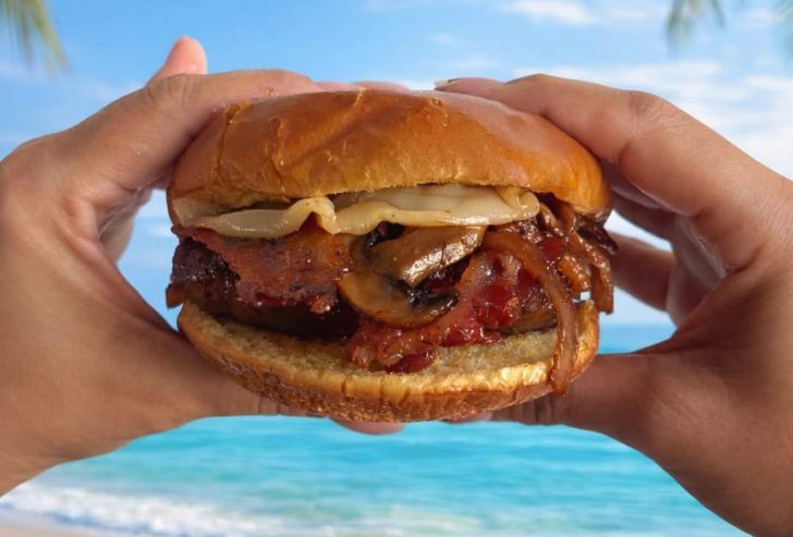 Burger Caramelizado de El Break sostenida frente al mar.