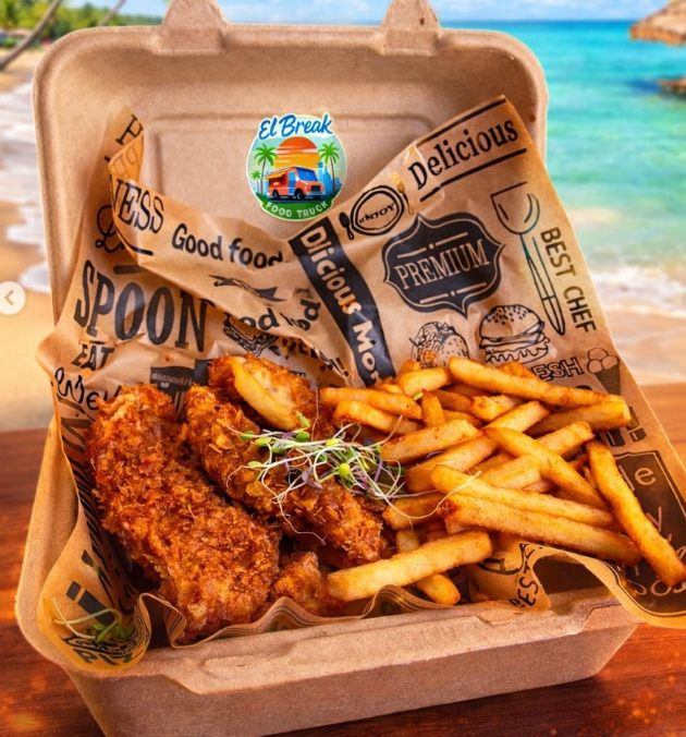 Tenders de pechuga empanados con papas fritas en envase, en la playa.